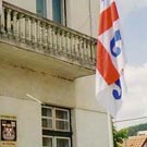 Flags and sign with greater arms in front of Surdulica municipality building